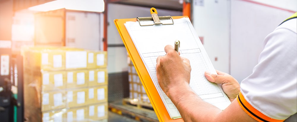 Arbeiter mit Notizblock für Fracht mit Spanngurten